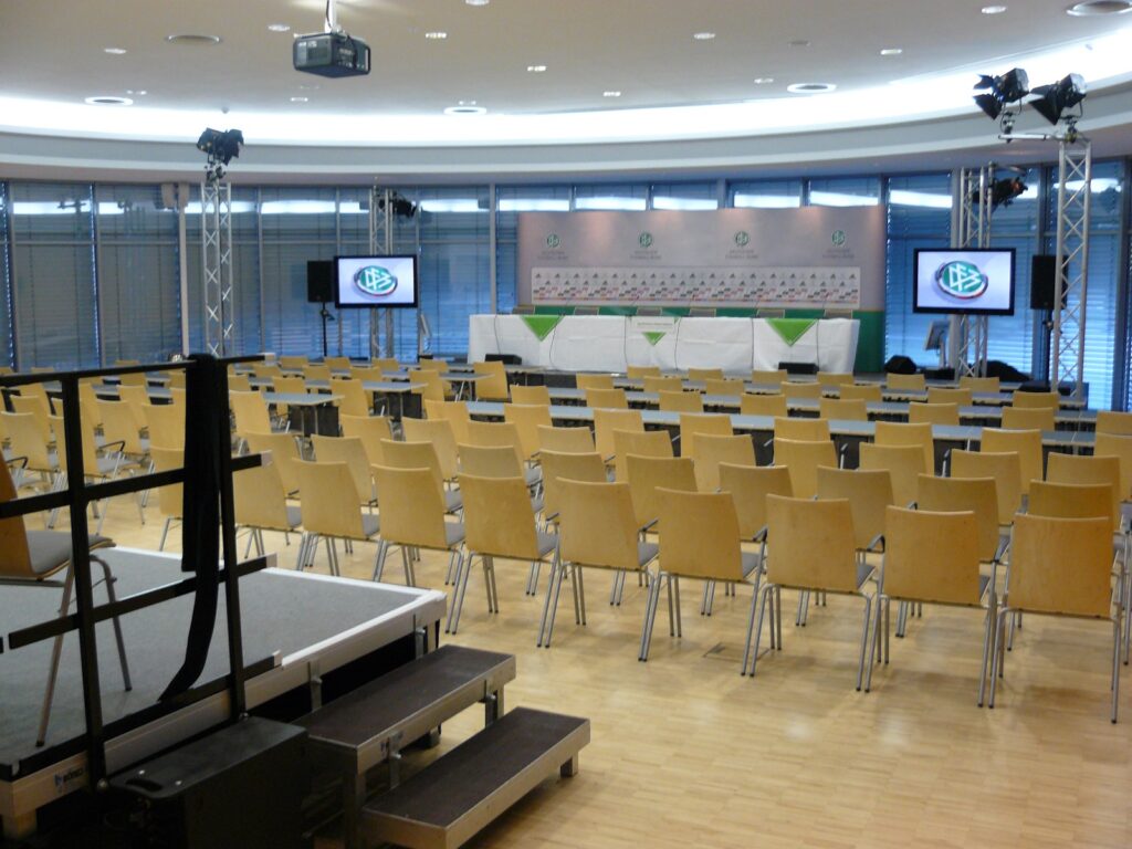 Aufgebauter Pressekonferenzraum mit Podium, Bildschirmen und Bestuhlung im Sportcentrum Kamen-Kaiserau